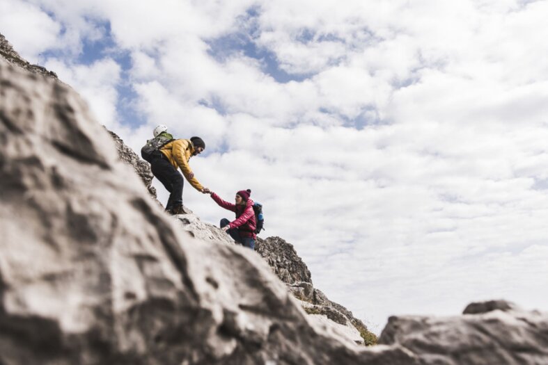 One climber helping another up the rock face